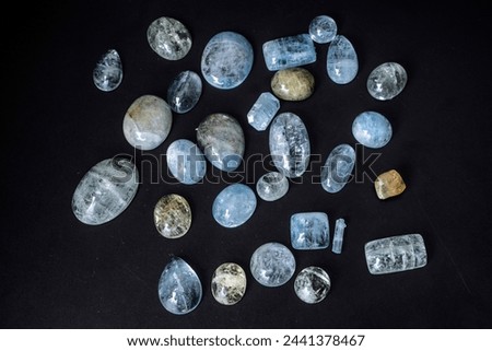 Aquamarines, precious semitransparent gemstones of delicate blue color. A set of several rare stones. Cabochons. Smooth, glossy, processed. Textured. Against a black background