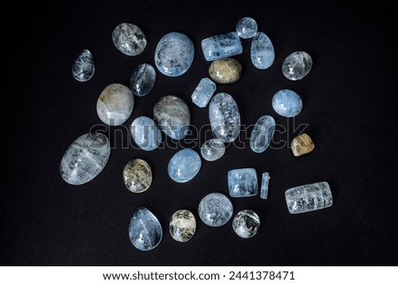 Aquamarines, precious semitransparent gemstones of delicate blue color. A set of several rare stones. Cabochons. Smooth, glossy, processed. Textured. Against a black background