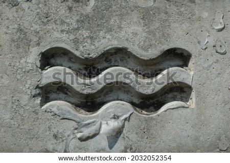 Aquarius symbol carved in stone. Rock carving of the eleventh sing of the zodiac. Zodiac sing, background, wallpaper.