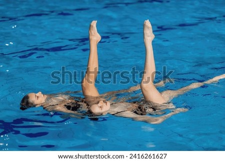 Aquatic poetry of a synchronized swimming duet, dancing in the shimmering pool waters, a perfect blend of grace and precision