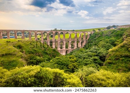 Aqueduct between mountains at sunset with cloudy sky in arcos del sitio in tepotzotlan state of mexico