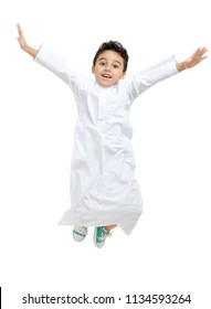 Arab Boy Jumping High With A Big Smile And Open Eyes, Wearing White Traditional Saudi Thobe And Sneakers, On White Isolated Background