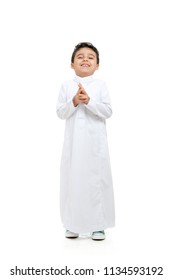 Arab boy laughing evil laugh, wearing white traditional Saudi Thobe and sneakers, on white isolated background