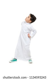 Arab boy looking up with a super hero stand, wearing white traditional Saudi Thobe and sneakers, on white isolated background