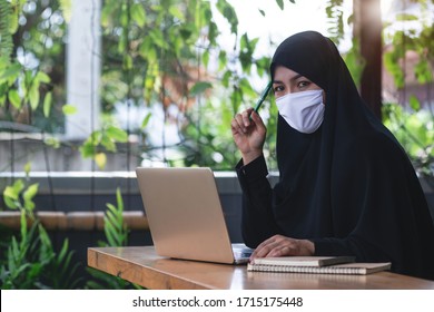 Arab Business Woman Working From Home Wearing Protective Mask With Laptop Computer, Looking At Camera