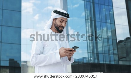 Arab businessman with high-rise buildings with glass windows as background. Arabic Man in Kandura Thobe Thawb for Middle Eastern corporate finance banking concept