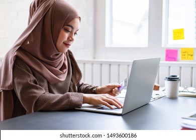 Arab businesswoman brown hijab shop online with a purple credit card on mockup white screen laptop at home. - Powered by Shutterstock