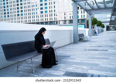 Arab Businesswoman Working On Laptop Sitting Outdoor. Muslim Saudi Arabian Woman In A Meeting Wearing Abaya And Hijab In Business Background