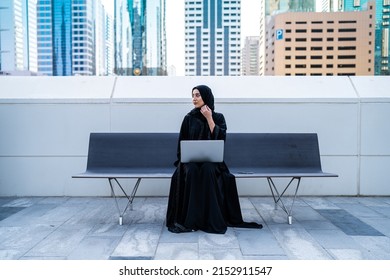 Arab Businesswoman Working On Laptop Sitting Outdoor. Muslim Saudi Arabian Woman In A Meeting Wearing Abaya And Hijab In Business Background