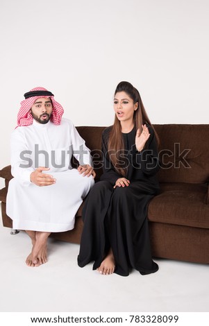 Arab couple fighting and discussing family issues while sitting on sofa chair at home with white background