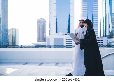 Arab couples or colleagues working together on tablet or laptop wearing traditional clothes and abaya. Muslim employees Saudi or Emirati business woman and man - Shutterstock ID 2161687851