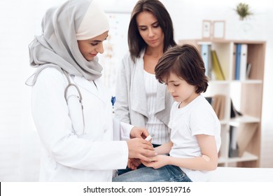 The Arab doctor examines the sick boy. He and his mother came to the hospital. Arabian hospital concept. Pediatrician office and sick child.