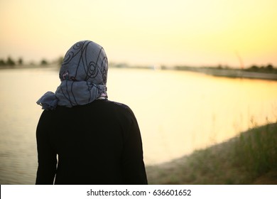 Arab, Emirate Indian, Asian Or Middle Eastern Woman. Girl Standing In Lake Side. Muslim Lady Standing Near Beautiful Landscape. Back Side Of Traditional Dress And Scarf, Young Adult Human Female.