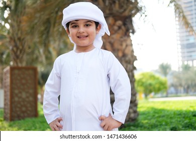 Arab Emirati boy student portrait wearing traditional middle eastern gulf kandora  ready to go to school while hands on this waist