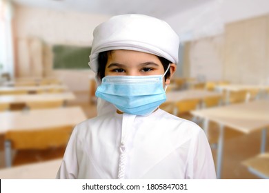 Arab Emirati Child Wearing Face Mask While Inside A School Classroom. Young Middle Eastern Boy On Traditional Kandura