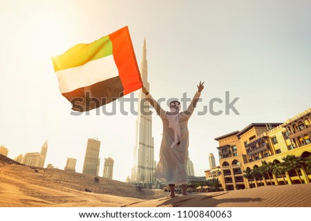 Arab Emirati man holding UAE flag front Burj Khalifa Dubai