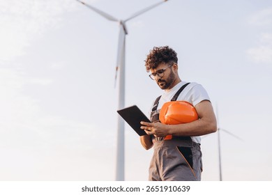 Arab engineer using digital tablet working near wind turbine for renewable and sustainable energy - Powered by Shutterstock - Get 15% off with code: PIKWIZARD15