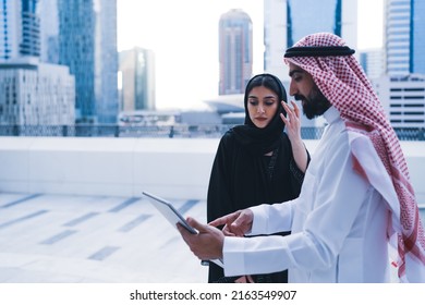 Arab Family Or Colleagues Working On Laptop Or Tablet Showing Looking In Business Background Wearing Traditional Abaya And Dress. Muslim Saudi Or Arabian People Teamwork Success.