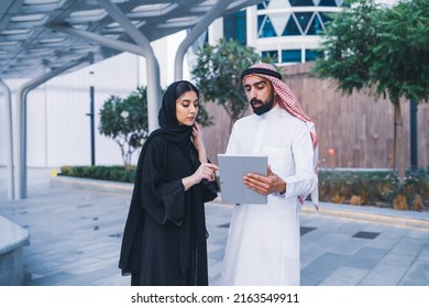 Arab family or colleagues working on laptop or tablet showing looking in business background wearing traditional abaya and dress. Muslim Saudi or Arabian people teamwork success. - Powered by Shutterstock