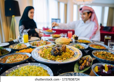 Arab Family In Traditional Clothes Eating During The Holy Month Of Ramadan At Iftar.Feast In Honor Of Eid Mubarak. The Family Sits On The Background Of A Table Filled With Traditional Food Eid Al Adha