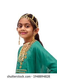 Arab girl dressed up for Eid festival wearing a traditional arabic green dress with gold ear ring, head and neck jewellery.