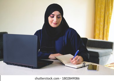 Arab girl writing notes wearing Abaya. Arabic Middle East student writes on a notebook for college university concept. Arabian businesswoman listing business corporate plans and checklist