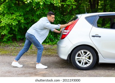 Arab Guy In Stylish Casual Outfit Pushing Broken Car, Side View. Middle-eastern Man Travelling With Friends Or Lover, Got Stuck On The Road To Countryside, Pushing Automobile Hatchback