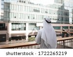 Arab guy wearing traditional kandura in urban city emirates lifestyle. Overlooking building from the balcony. Photography concept for Arab magazine.