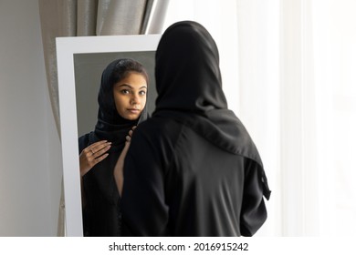 An Arab lady checking the mirror and setting her dress