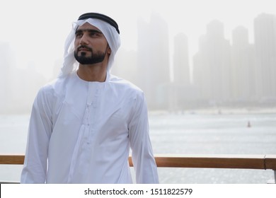 Arab male model looking up wearing Emirati dress and ghutra turban with copy space background