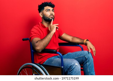 Arab man with beard sitting on wheelchair thinking concentrated about doubt with finger on chin and looking up wondering 