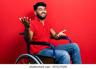 Arab man with beard sitting on wheelchair smiling cheerful with open arms as friendly welcome, positive and confident greetings 