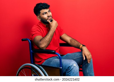 Arab man with beard sitting on wheelchair thinking worried about a question, concerned and nervous with hand on chin 