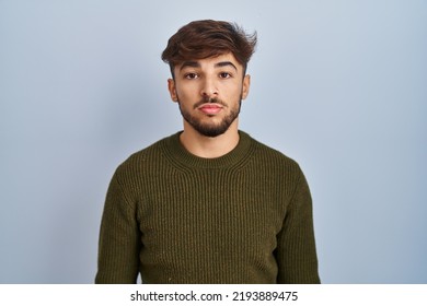 Arab Man With Beard Standing Over Blue Background Relaxed With Serious Expression On Face. Simple And Natural Looking At The Camera. 