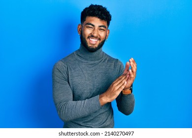 Arab Man With Beard Wearing Turtleneck Sweater Clapping And Applauding Happy And Joyful, Smiling Proud Hands Together 