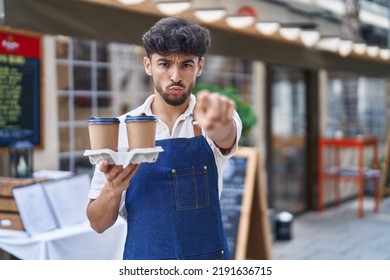 Arab Man With Beard Wearing Waiter Apron At Restaurant Terrace Pointing With Finger To The Camera And To You, Confident Gesture Looking Serious 