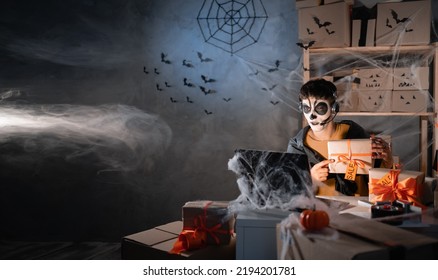 Arab Man Business Owner Wears White Clay Skull, Professional Makeup In Home Office. Accepts An Order On The Site Writes The Address On The Box. Festive Decorated Office. Halloween Sale Concept. Banner