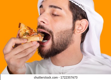 Arab Man Eating A Pizza. He Opened His Mouth, Holding A Pizza Triangle In His Right Hand. Isolated On Yellow Background.