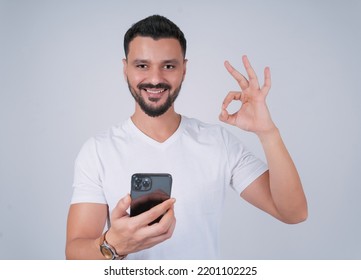 Arab Man Holding Mobile And Making Okay Symbol With His Hand