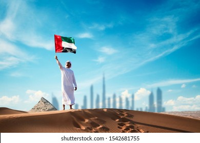 Arab man holding the UAE flag in the desert celebrating UAE national day and Uae flag day.