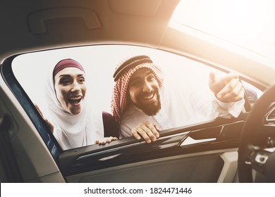 Arab Man Shows Something To A Woman In A Hijab. Arab Man With Wife Looks Inside A New Car At A Car Dealership. 