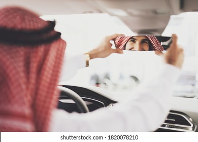 Arab Man Sits In A New Car And Adjusts The Mirror. Arab Man In Car Dealership Checks Car For Purchase. 