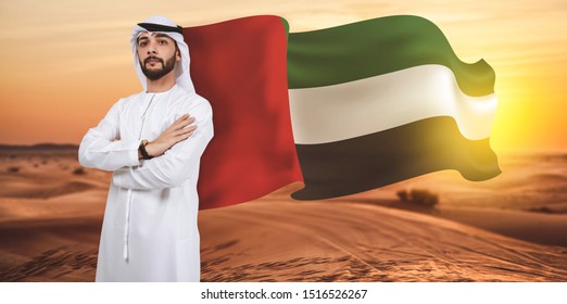 Arab Man Standing On Desert Evening With UAE Flag Waving Behind 