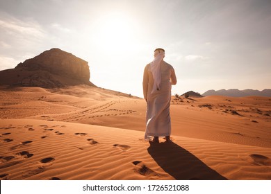 Arab man stands alone in the desert and watching the sunset.