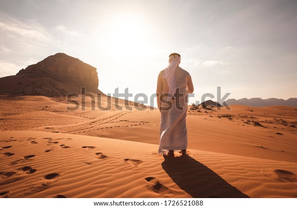 Arab man stands alone in the desert and watching\
the sunset.