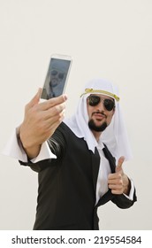 Arab Man Taking Selfie With Smart Phone In Outdoors White Wall