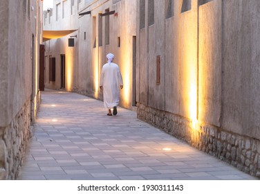 Arab man in traditional clothing walking in historic part of Dubai
