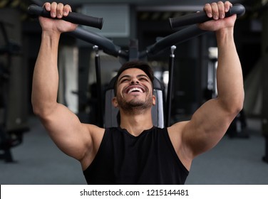 Arab man training hard at gym, doing workout on fitness machine
