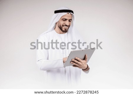 Arab man using phone or laptop wearing traditional isolated on white.