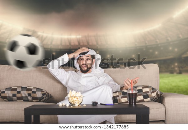 Arab man watching Soccer on 3D TV,\
Arabic\
football concept.